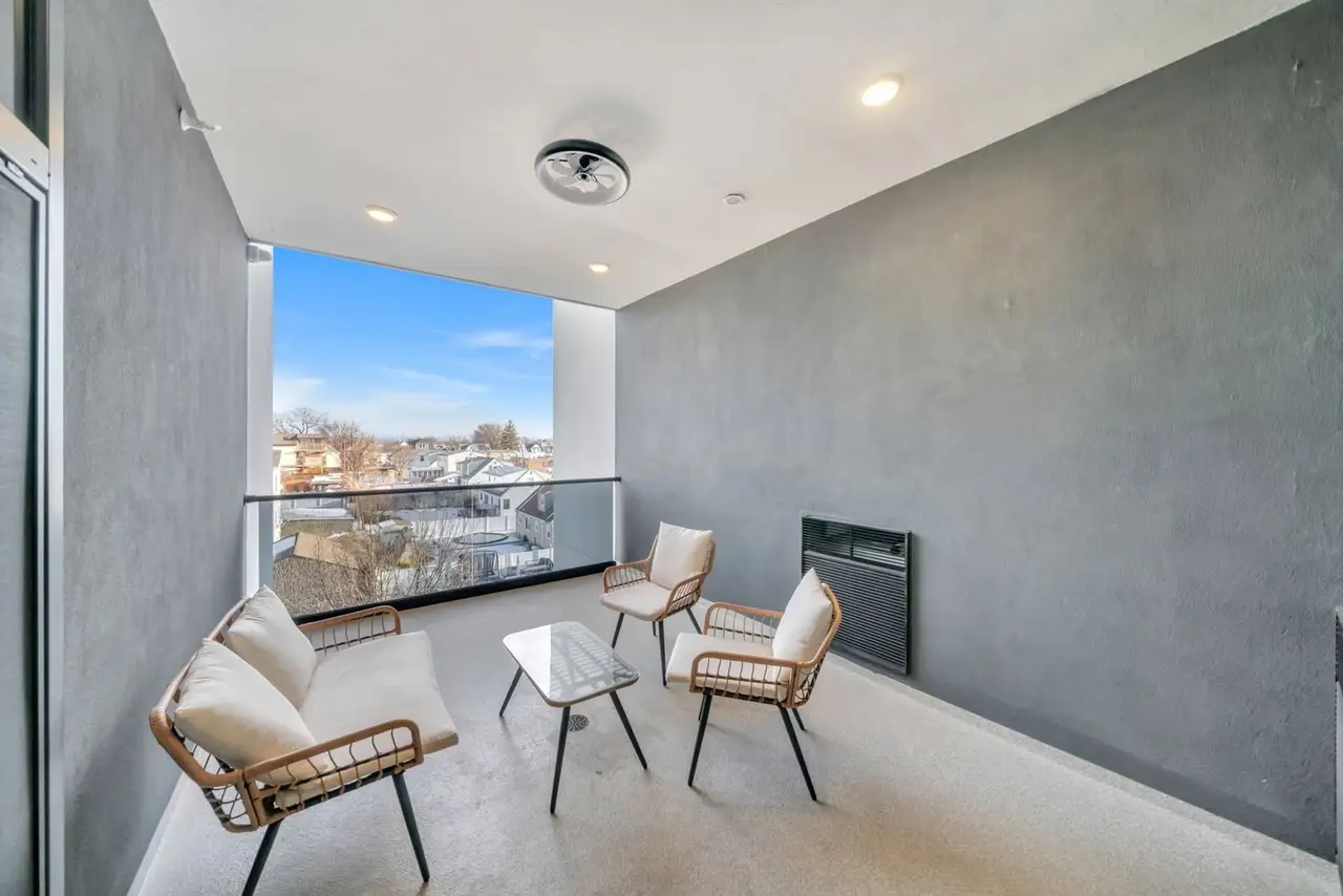Terrace room with rattan chairs, grey wall and a window view over rooftops